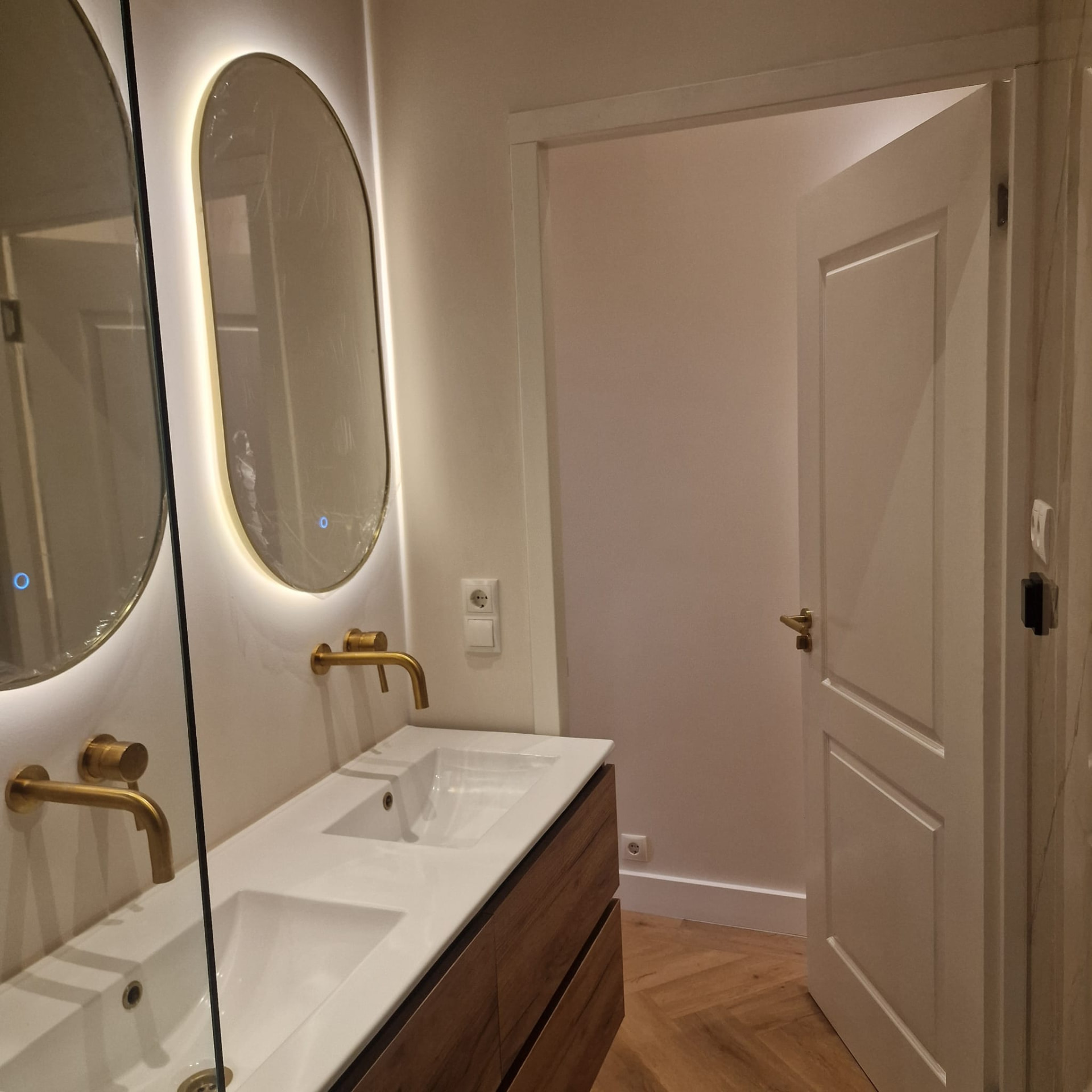 Badkamer met ovale LED-spiegels en messing kranen