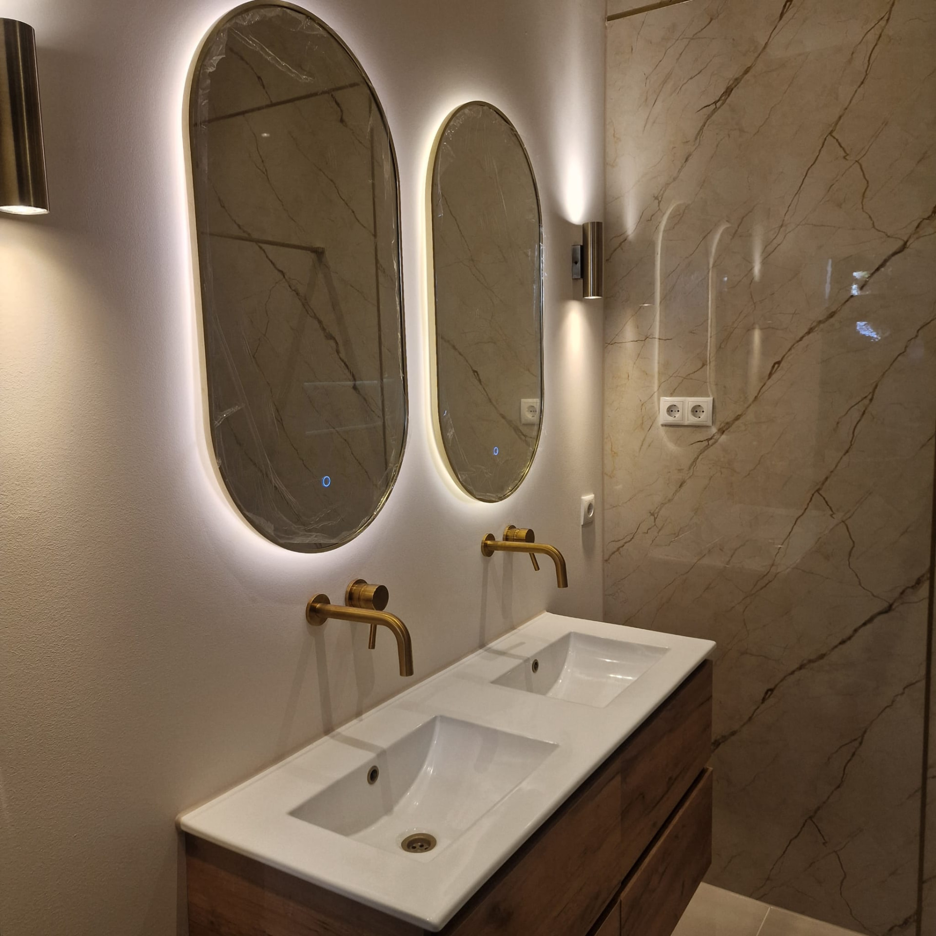 Badkamer met marmeren wand en dubbele wastafel
