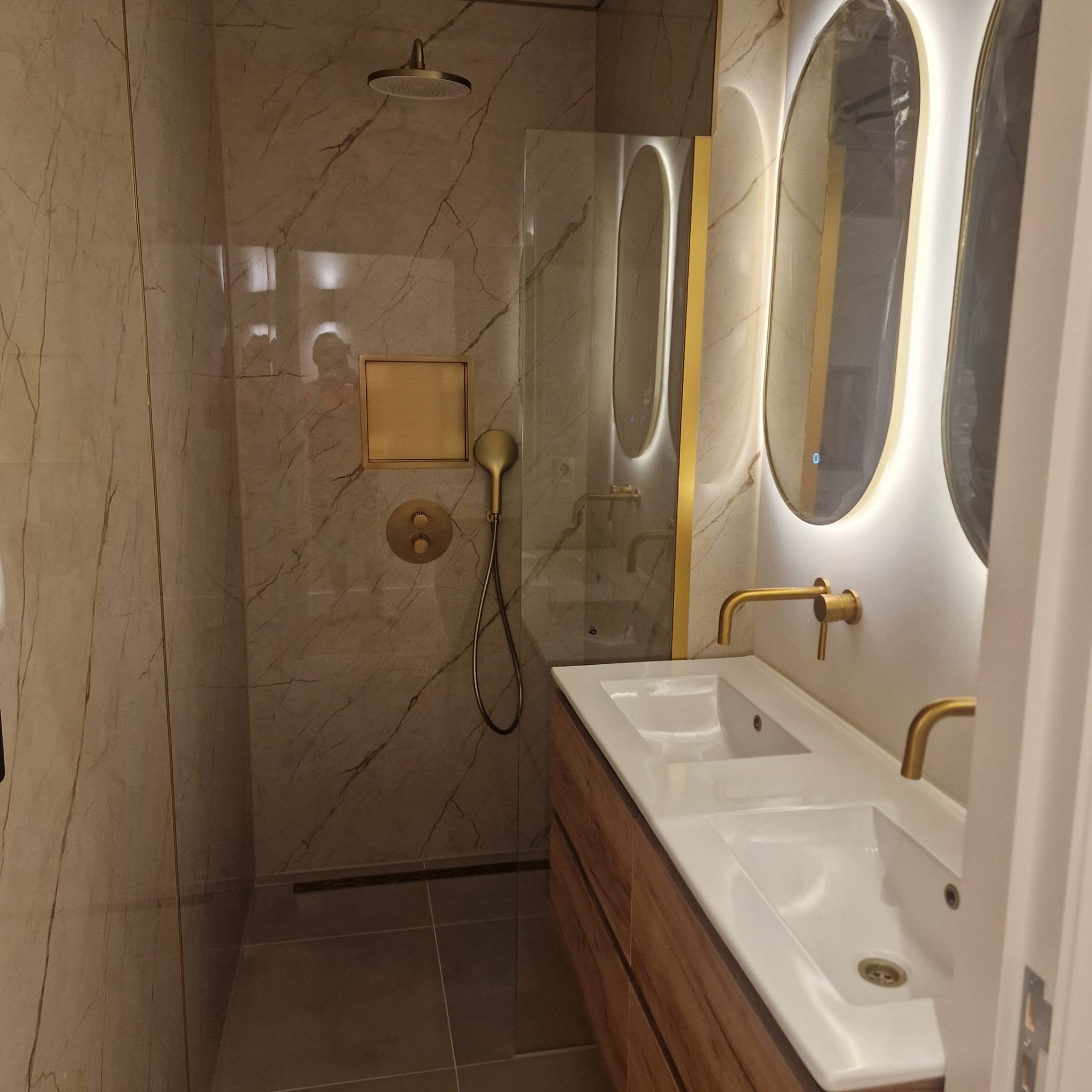Marmeren badkamer met inbouwnis en messing kranen
