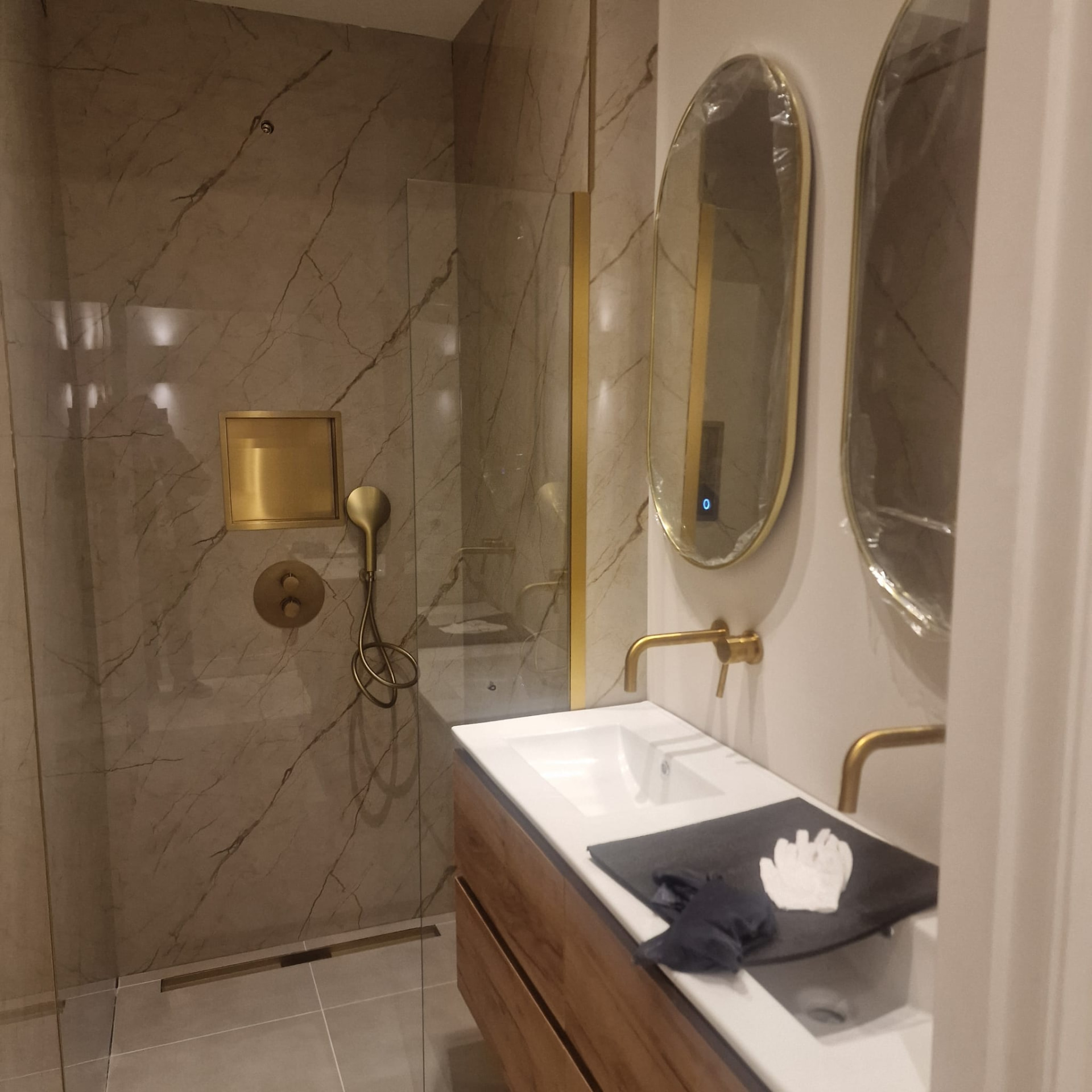 Badkamer met glazen douchewand en houten meubel
