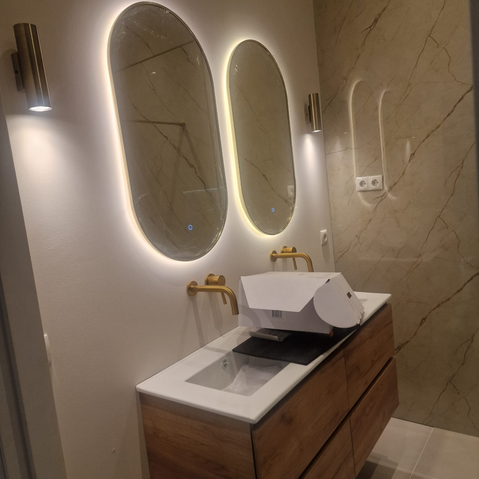 Badkamer met ovale spiegels en wandverlichting
