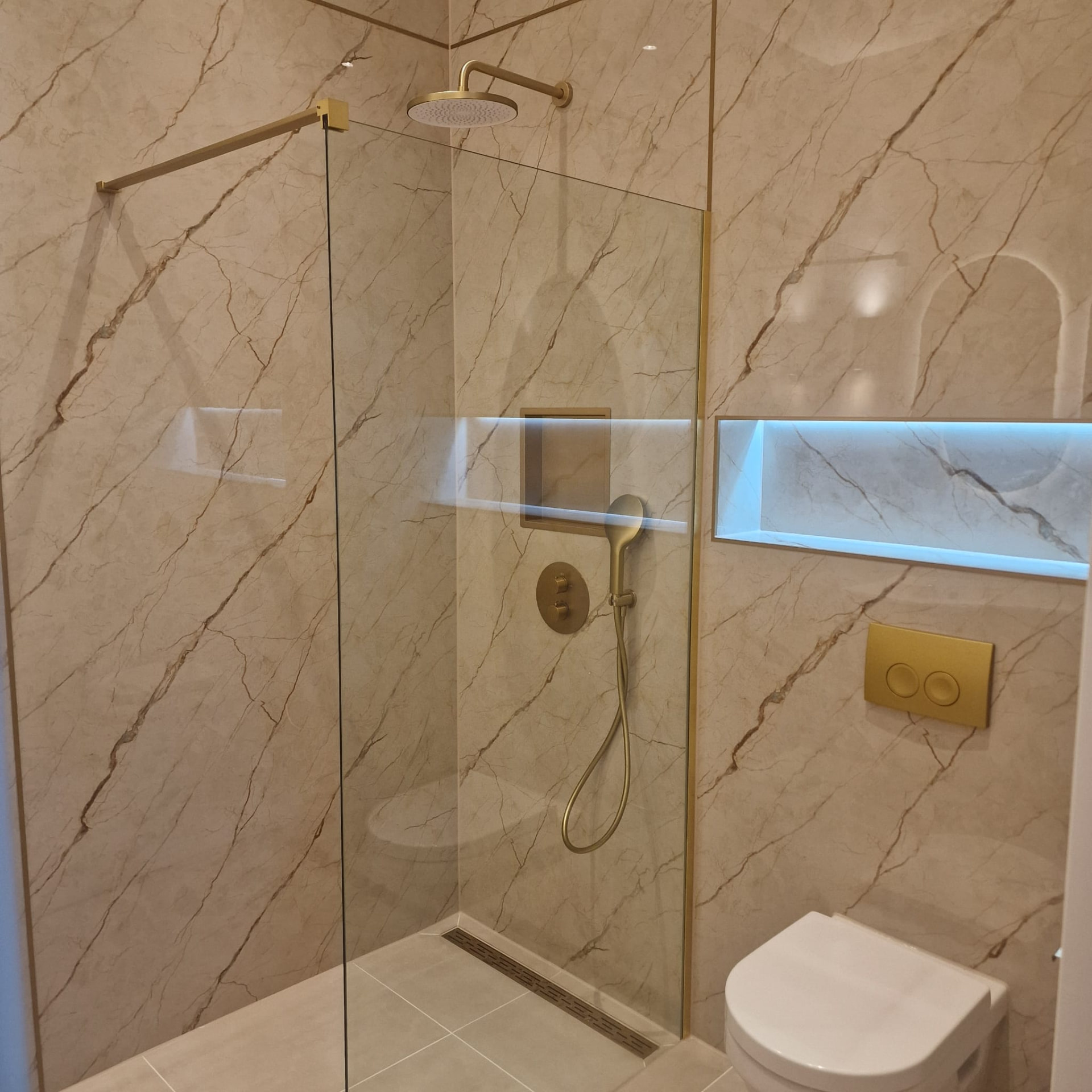 Doucheruimte met glazen wand en verlichte nis