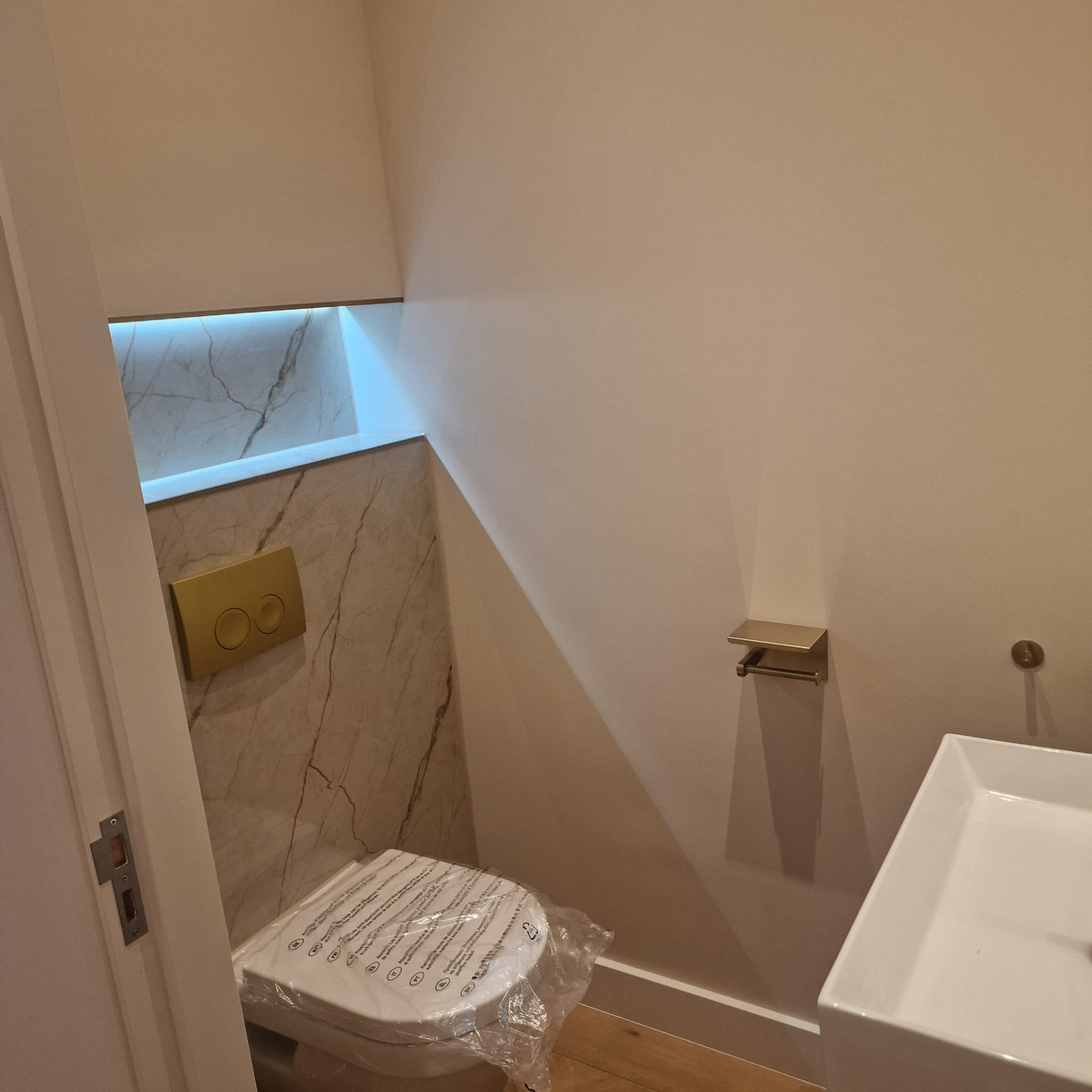 Toiletruimte met marmerlook wand en LED-nis
