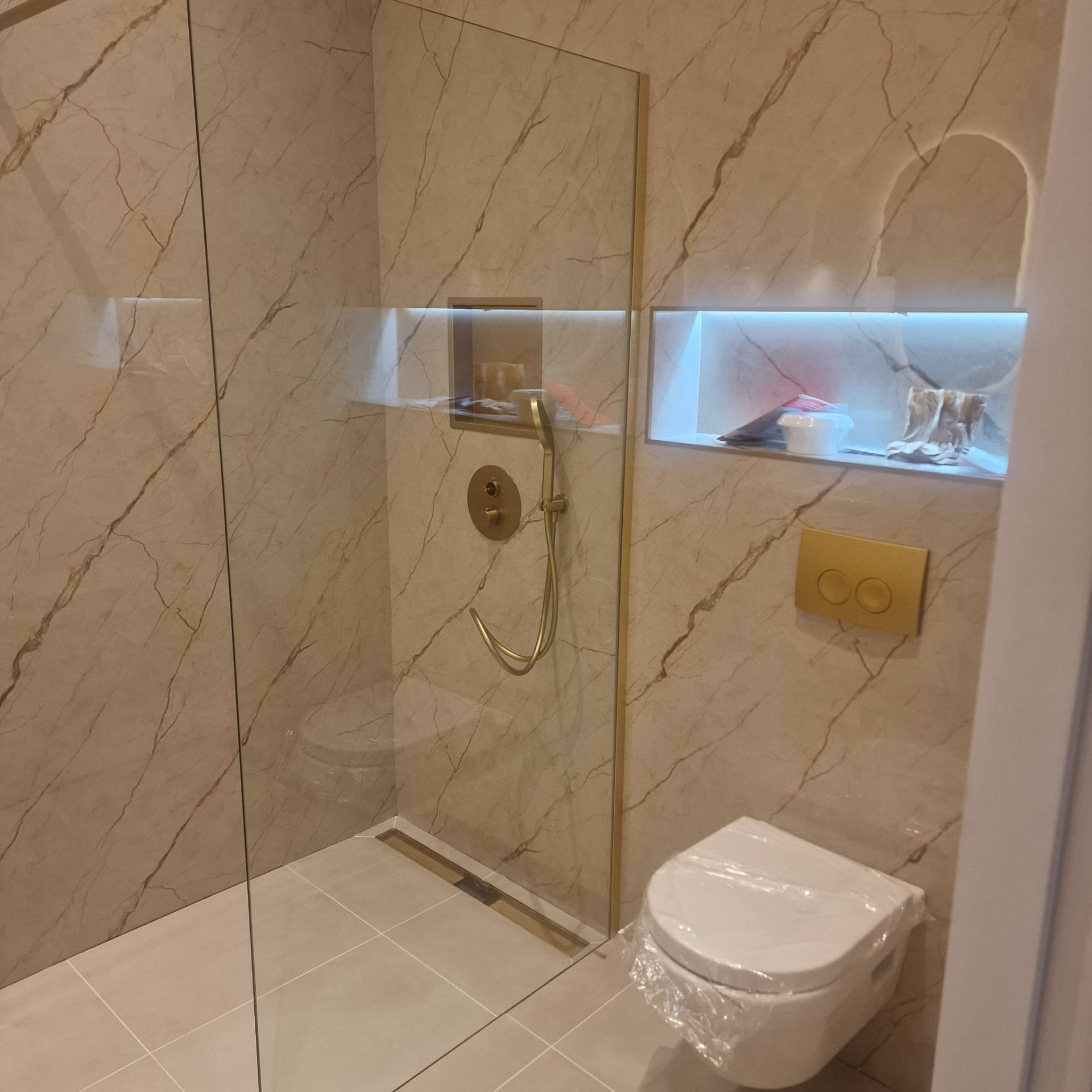Badkamer met inloopdouche, hangtoilet en messing details