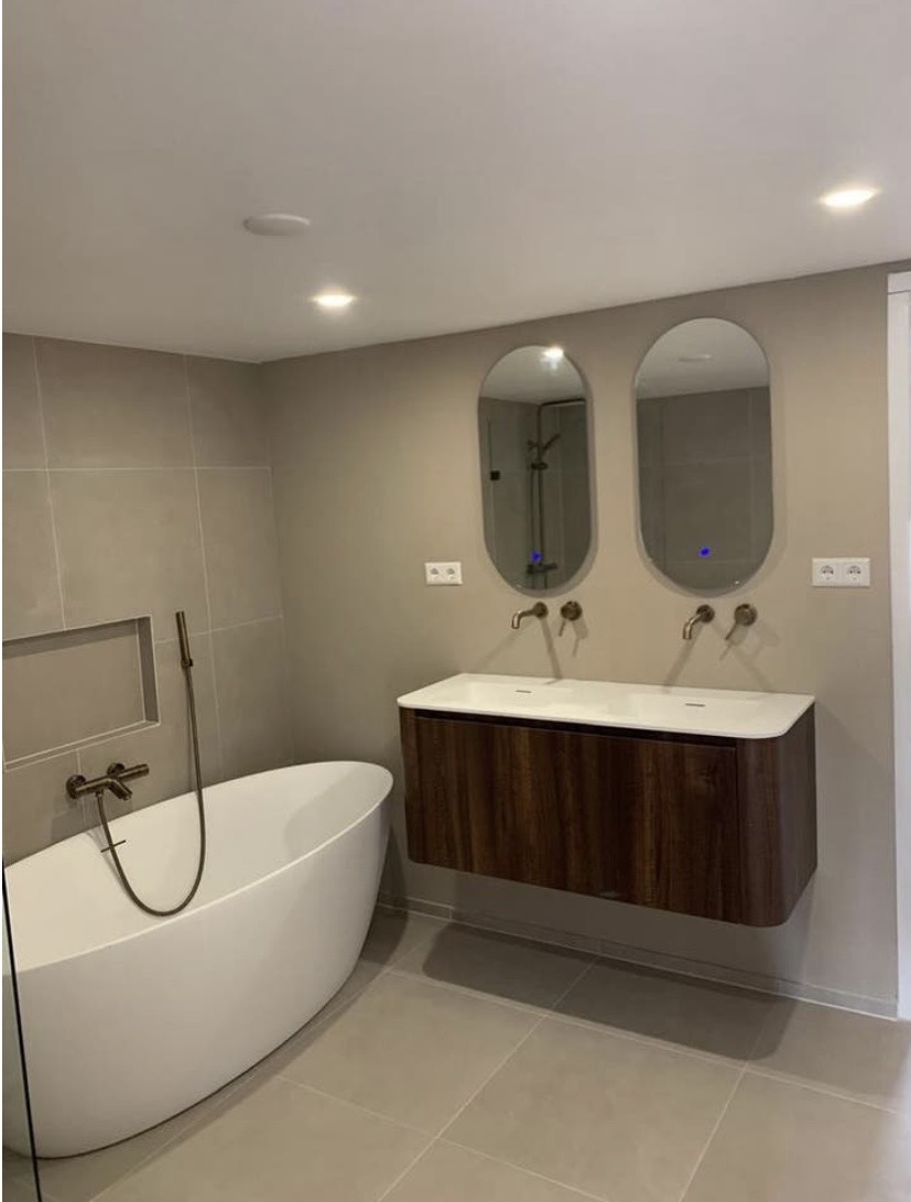 Badkamer met ovale spiegels en houten meubel